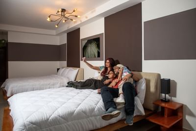 Family taking a selfie while sitting on a bed in a room at MARINN Tropical Vibes Hotel