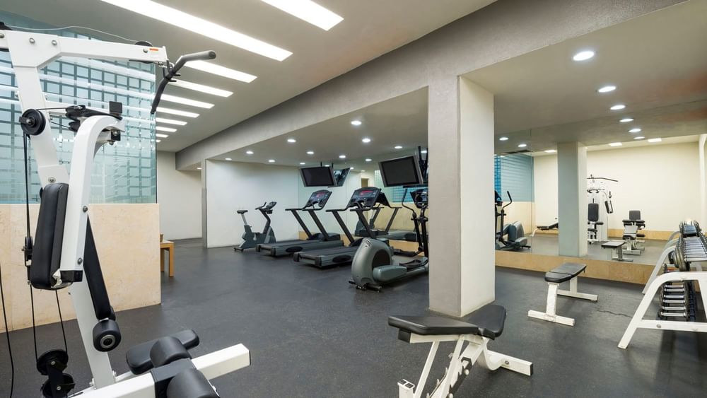 Spacious gym featuring treadmills, weight machines, and large mirrors for guest workouts at Real Inn Perinorte