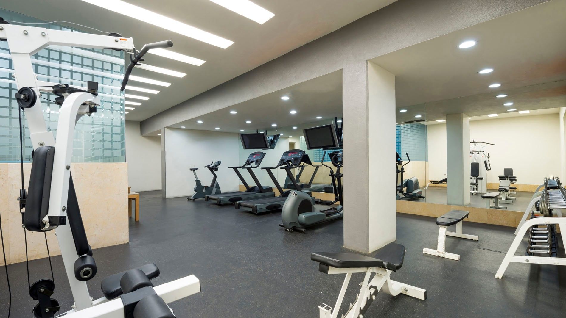 Spacious gym featuring treadmills, weight machines, and large mirrors for guest workouts at Real Inn Perinorte