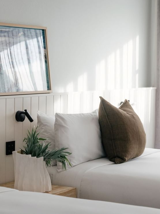 Atrium Two Bedroom at Elysium Hotels with twin beds by framed ocean art under a black wall-mounted reading lamp