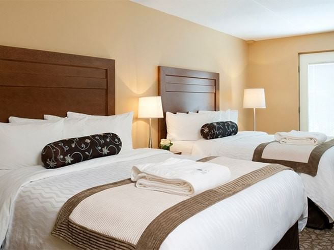 Queen beds with cozy pillows by the nightstand in Standard Two Queen Beds with Balcony at Temple Gardens Hotel & Spa