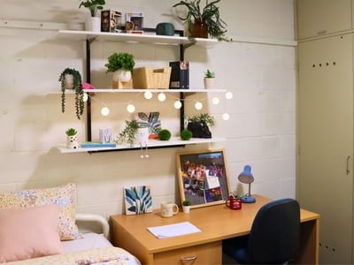 A neatly organized dorm room at La Trobe University with desk, shelves, and bed.