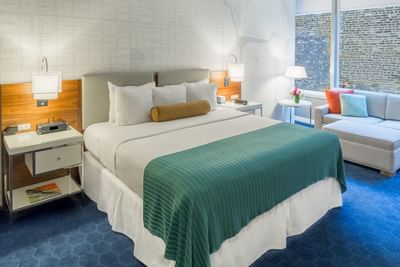 Bed, nightstands & a sofa in Deluxe King Room at Kinzie Hotel