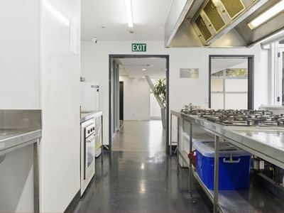 Modern kitchen with commercial stove, oven, and sinks at Student Living Auckland Anzac.