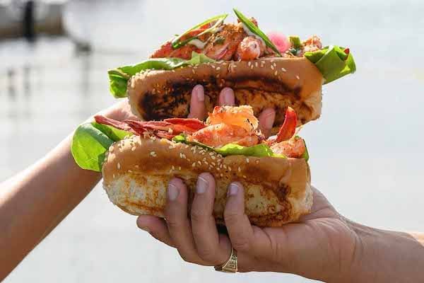 Two hands holding lobster rolls