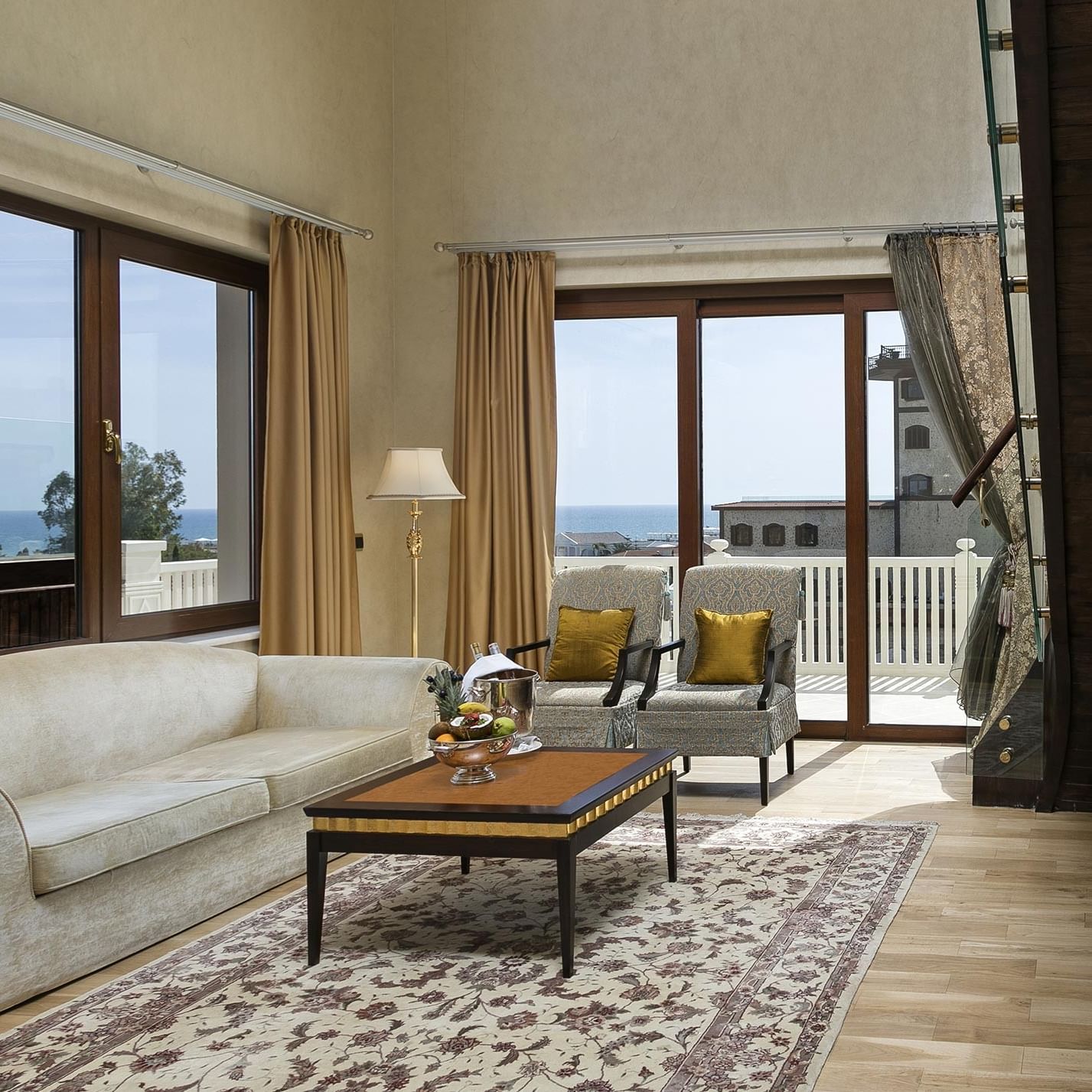 В гостиной королевского двухуровневого люкса есть диван, журнальный столик, кресла и большие окна с видом на море