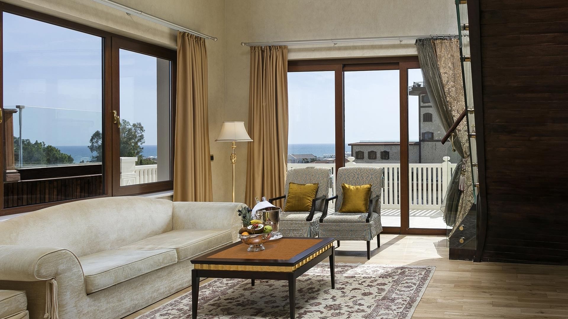 В гостиной королевского двухуровневого люкса есть диван, журнальный столик, кресла и большие окна с видом на море