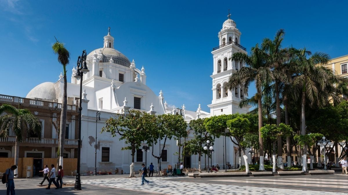 Daytime photo of the neoclassical Veracruz Cathedral and its bell tower, overlooking the palm tree-lined Zocalo square in Veracruz near Camino Real Veracruz