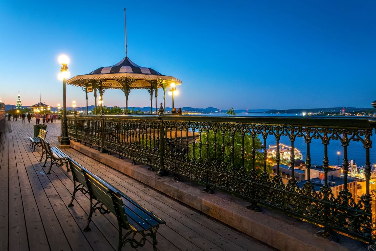 Terrasse en bois avec bancs et kiosque au bord de l'eau au crépuscule à Warwick Le Crystal Montreal
