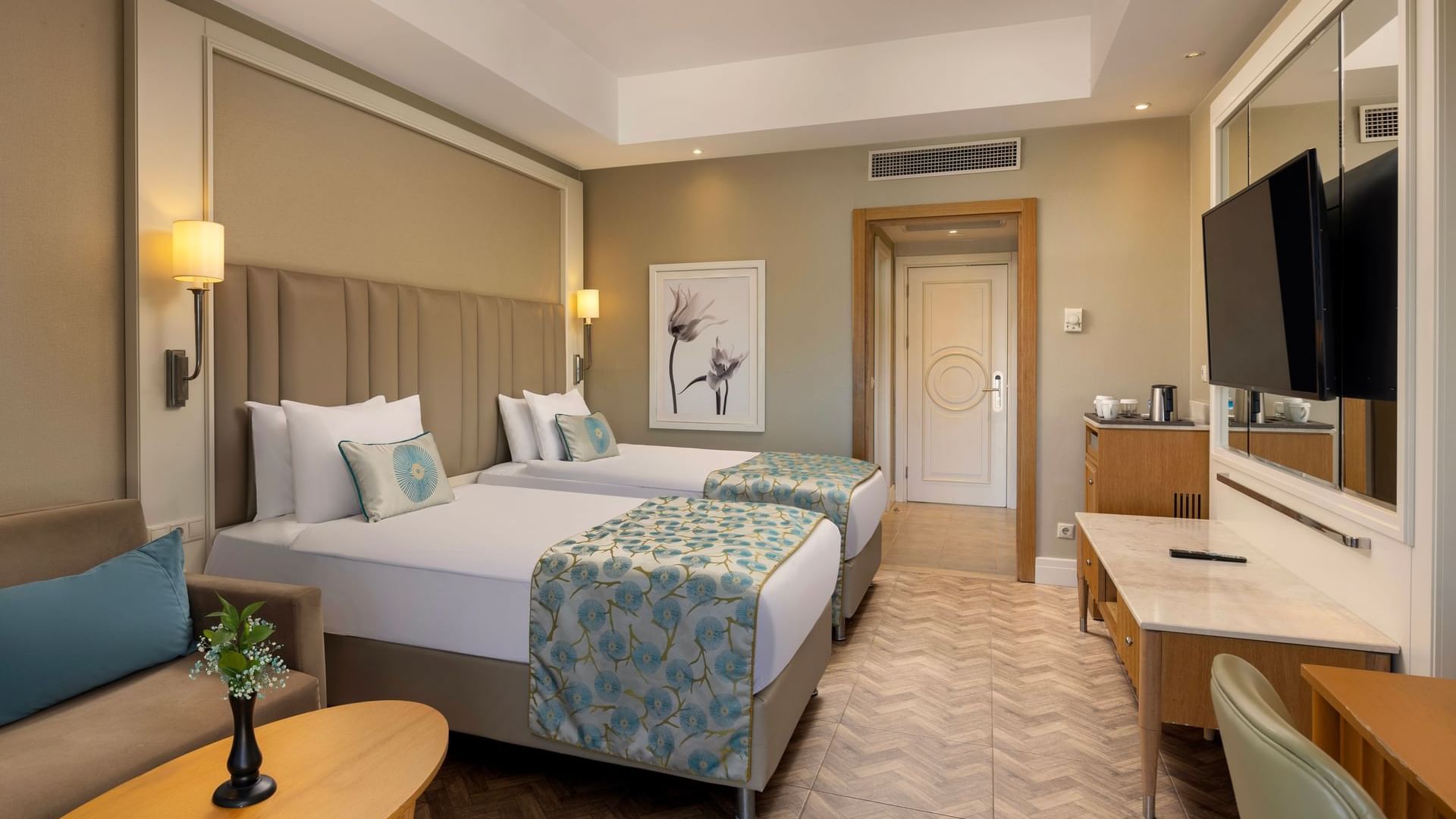 A refined hotel room with two beds, a sofa, and a wall-mounted TV at Titanic Deluxe Lara.