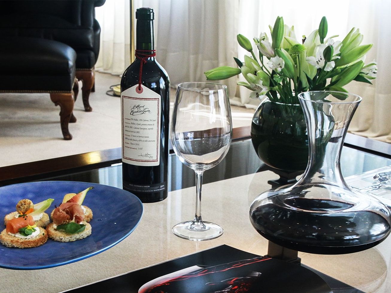 Una botella de vino, una copa y unas tartas en Hotel Emperador Buenos