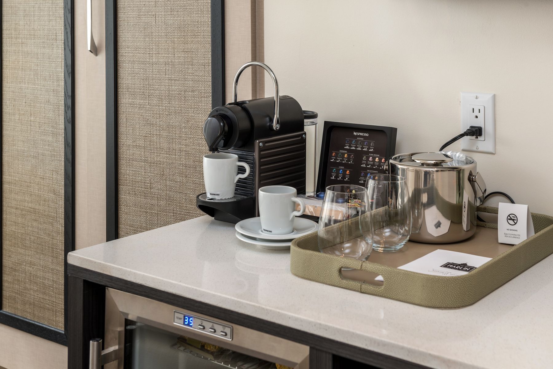 A hotel room's minibar with a coffee maker, electric kettle, and glasses.