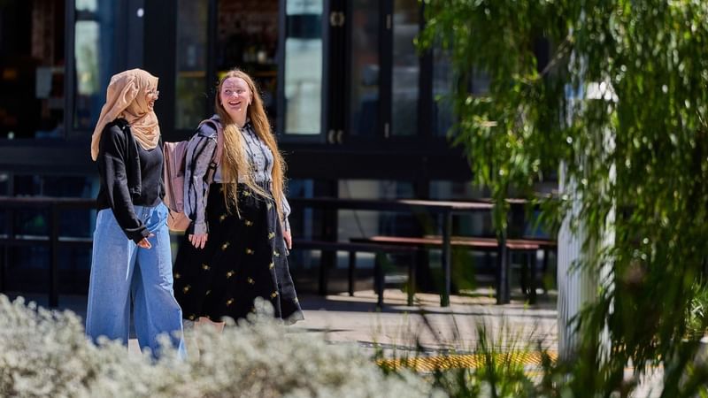 Two female students walking outside a UniLodge student accommodation building