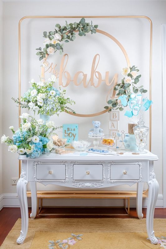 Baby shower table featuring blue and white decor, a floral arrangement and sweet treats at Park Hyatt Saigon