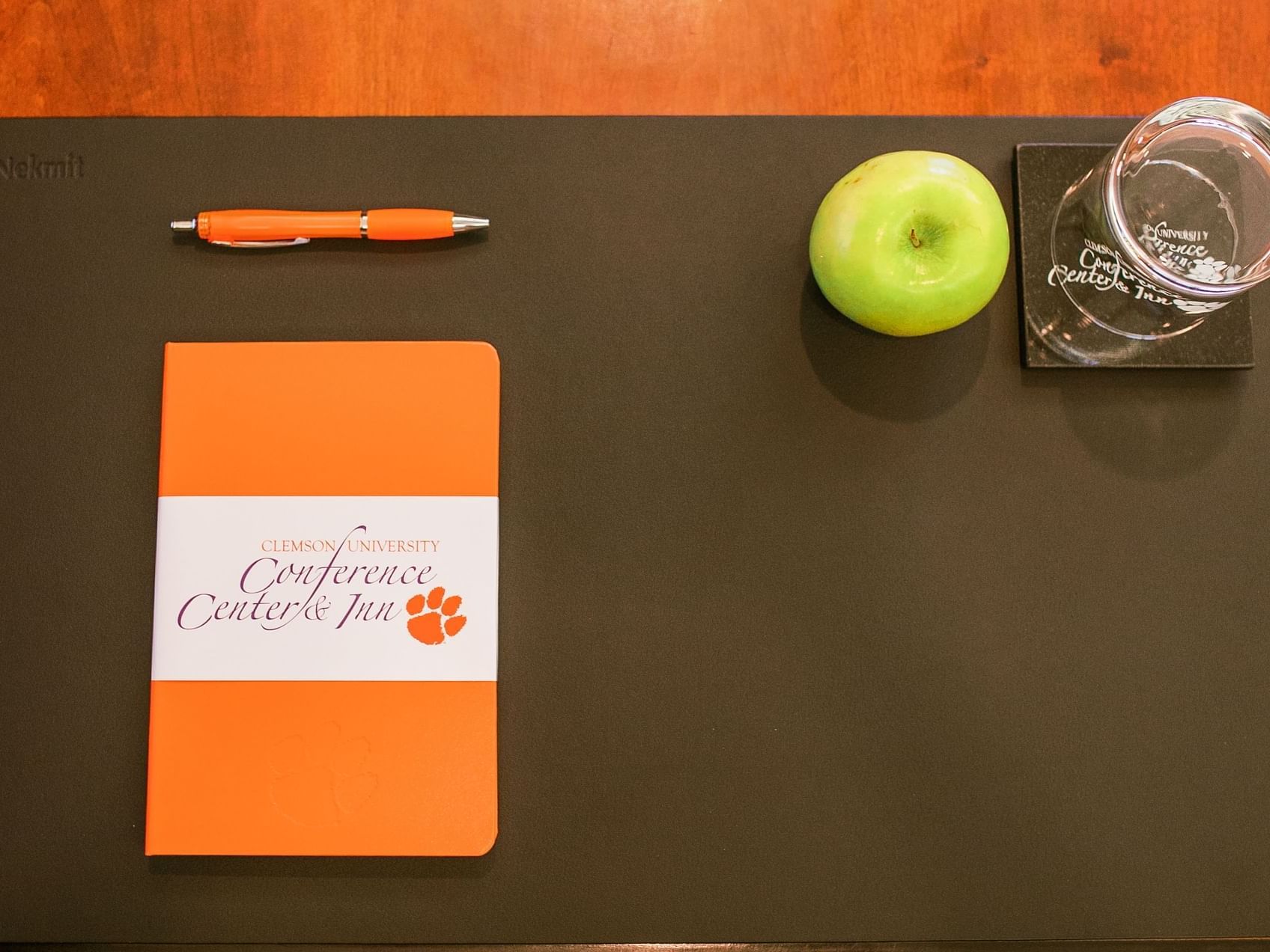 Notebook with pen, apple, coaster with glass, on a pad on table top