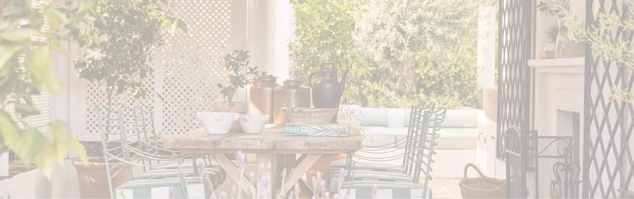 Bright Marbella Club outdoor dining patio with a rustic wooden table, metal chairs, and decorative bronze pots