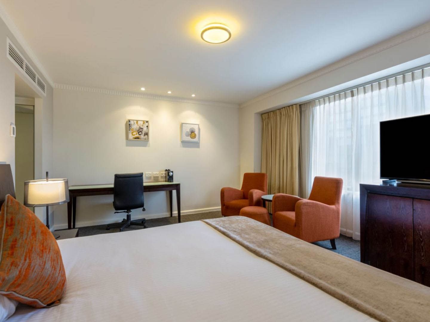 Comfy bed, TV and working table with sitting area in Executive King Plus at Grand Chancellor Adelaide