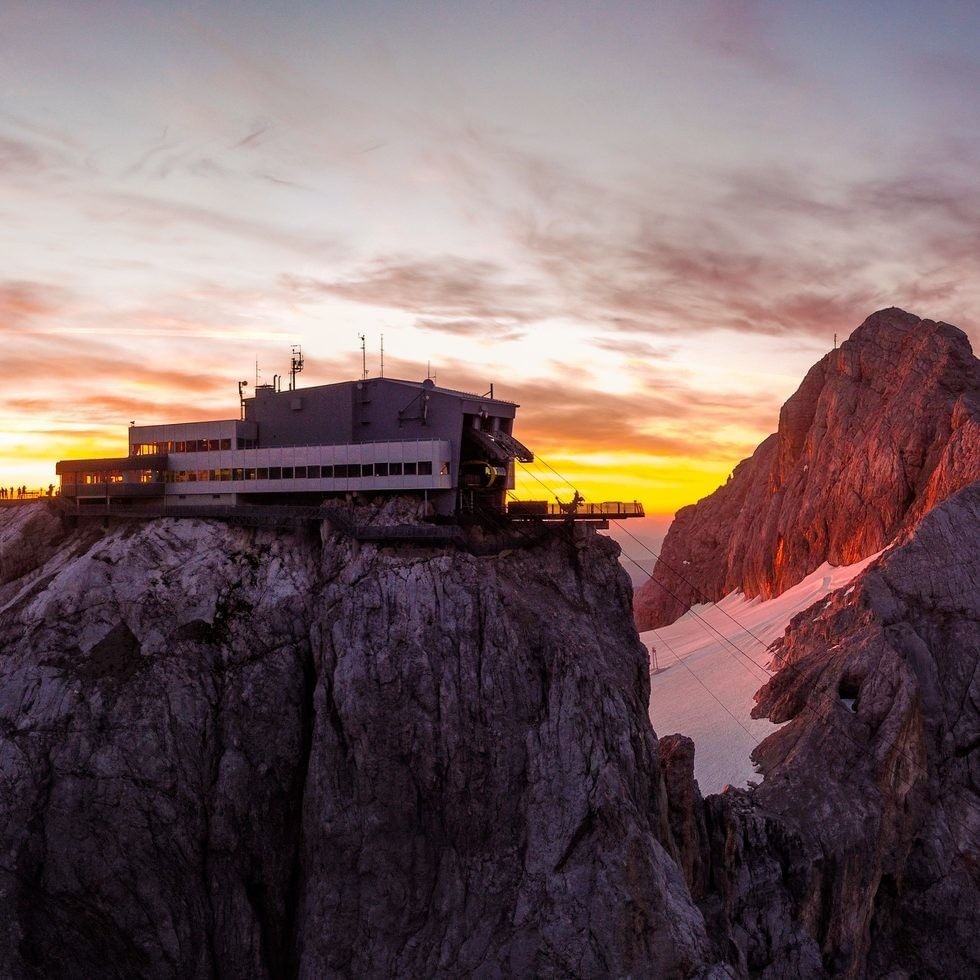 Sunset over mountain with cable car and building on the edge during Long Night of the Cable Car.