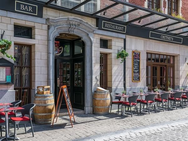 Outdoor terrace seating with comfortable chairs positioned along the elegant stone facade at The Chutney\’s Restaurant