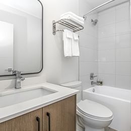 Bright hotel bathroom with sink, toilet, and shower-tub combination