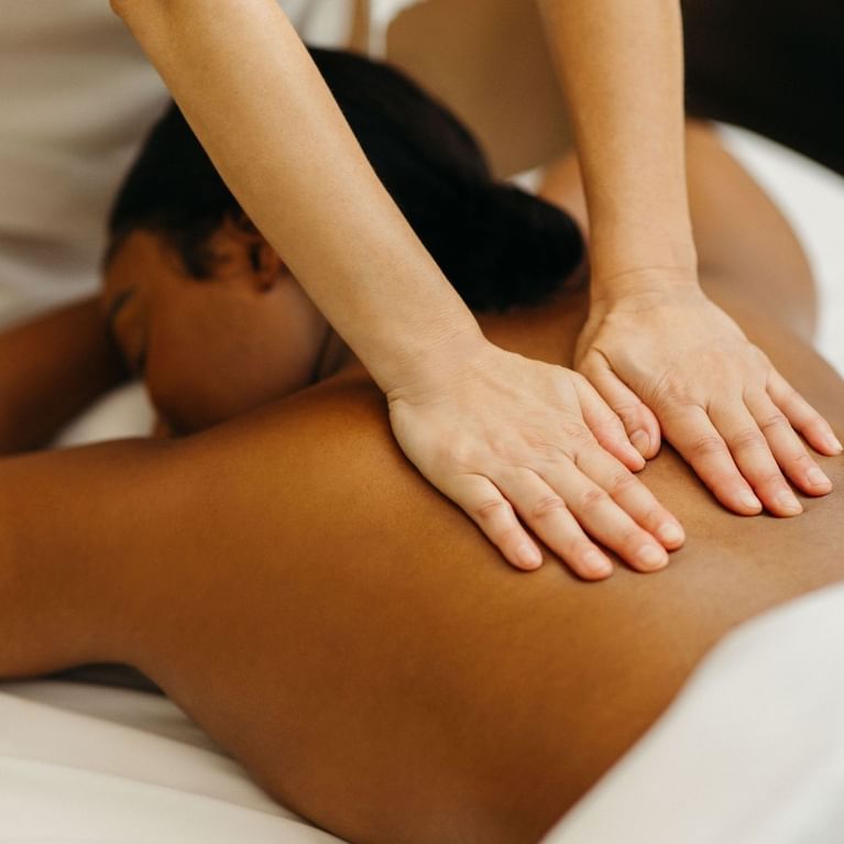 Massage therapist performing a back massage on a guest lying on a treatment table at Guerlain Spa