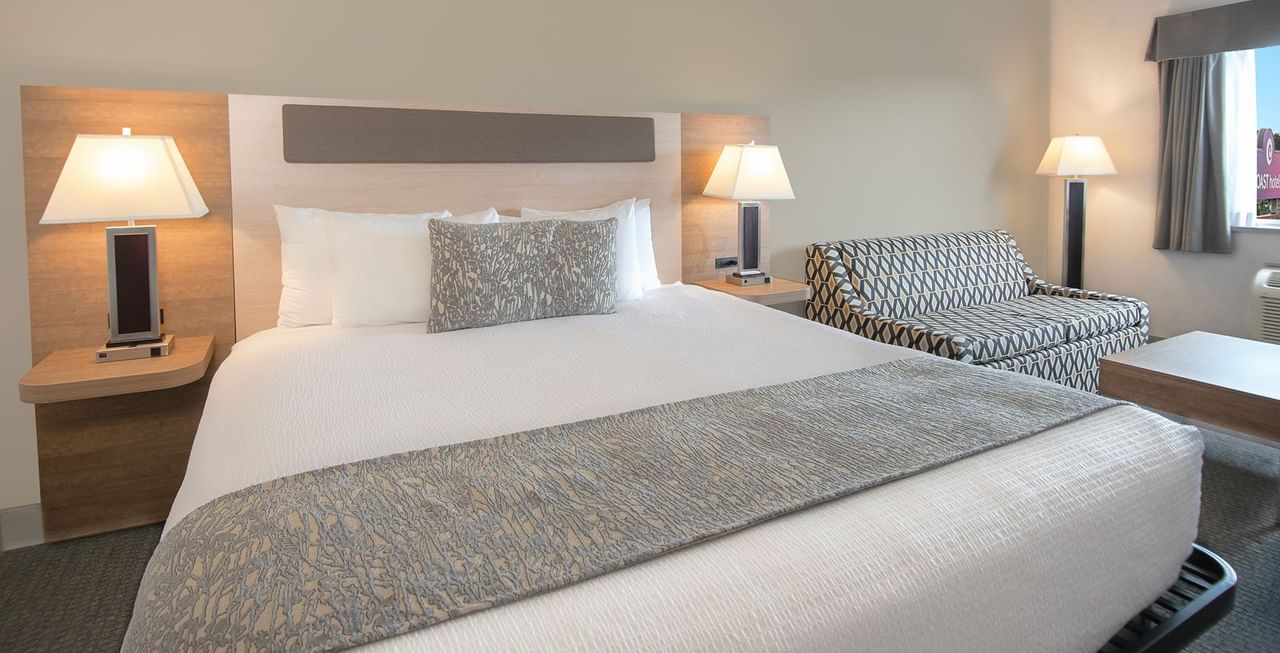 Hotel room with king bed, bedside table lamp, couch, and coffee table