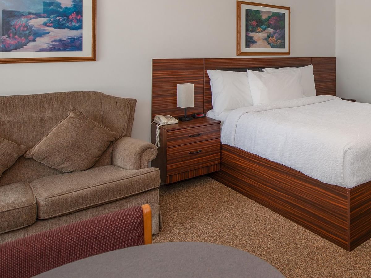 Guest room with a queen bed, sofa and wall art