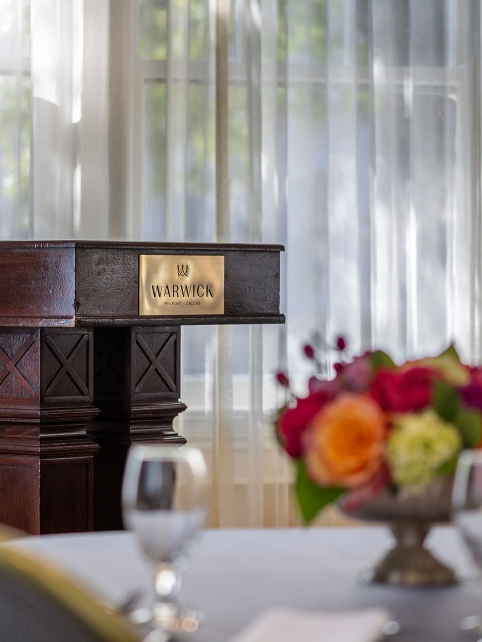 Elegant setup with podium, floral centerpiece, and wine glasses at Warwick Melrose in Dallas.