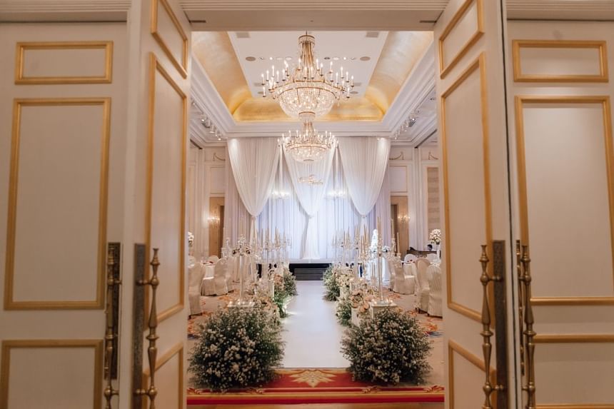 Wedding venue entrance featuring chandeliers, draped curtains, and floral centerpieces along the aisle at Park Hyatt Saigon