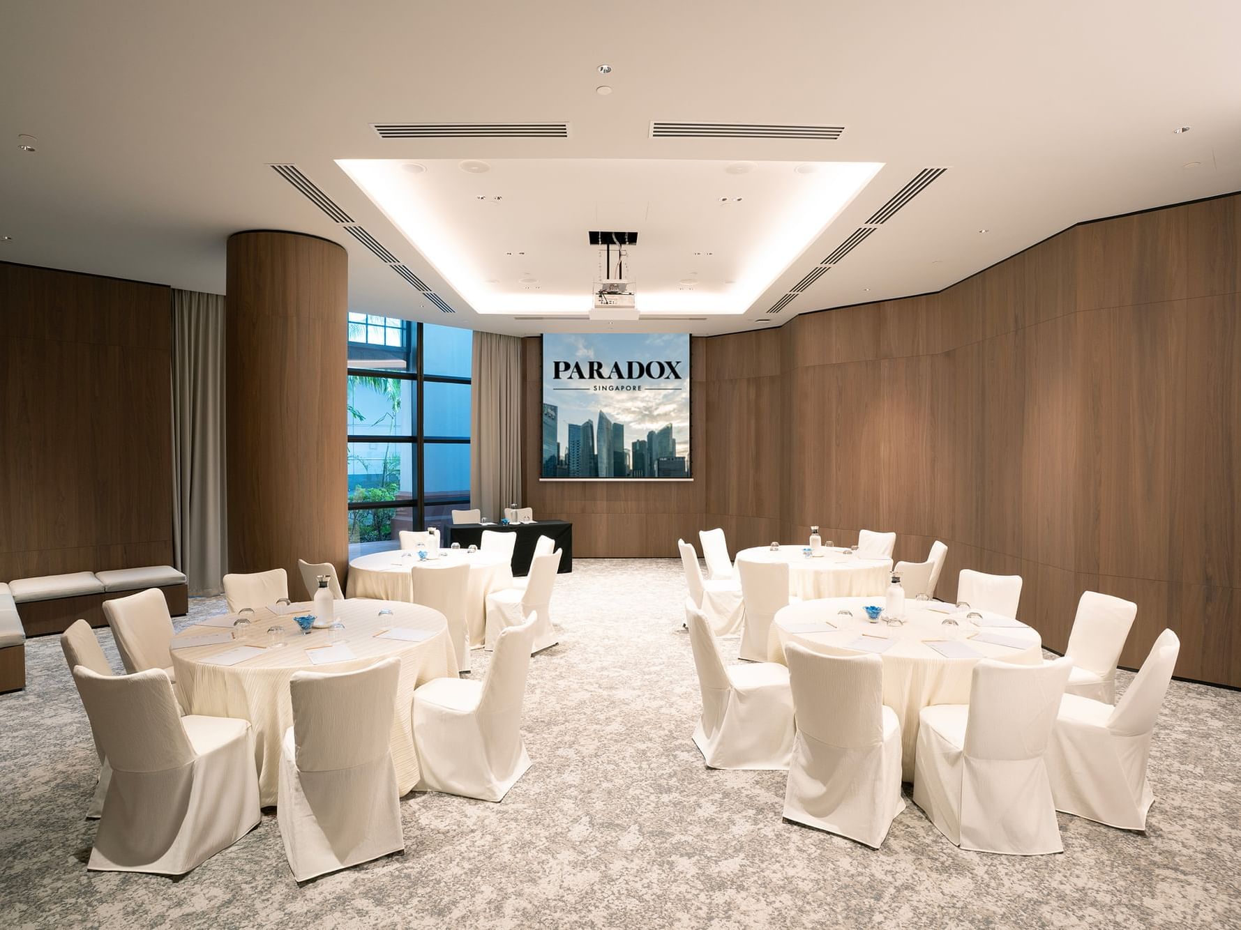 Cluster-style meeting room setup in the Sandalwood at Paradox Singapore, featuring neatly arranged tables, chairs, and professional conference amenities.
