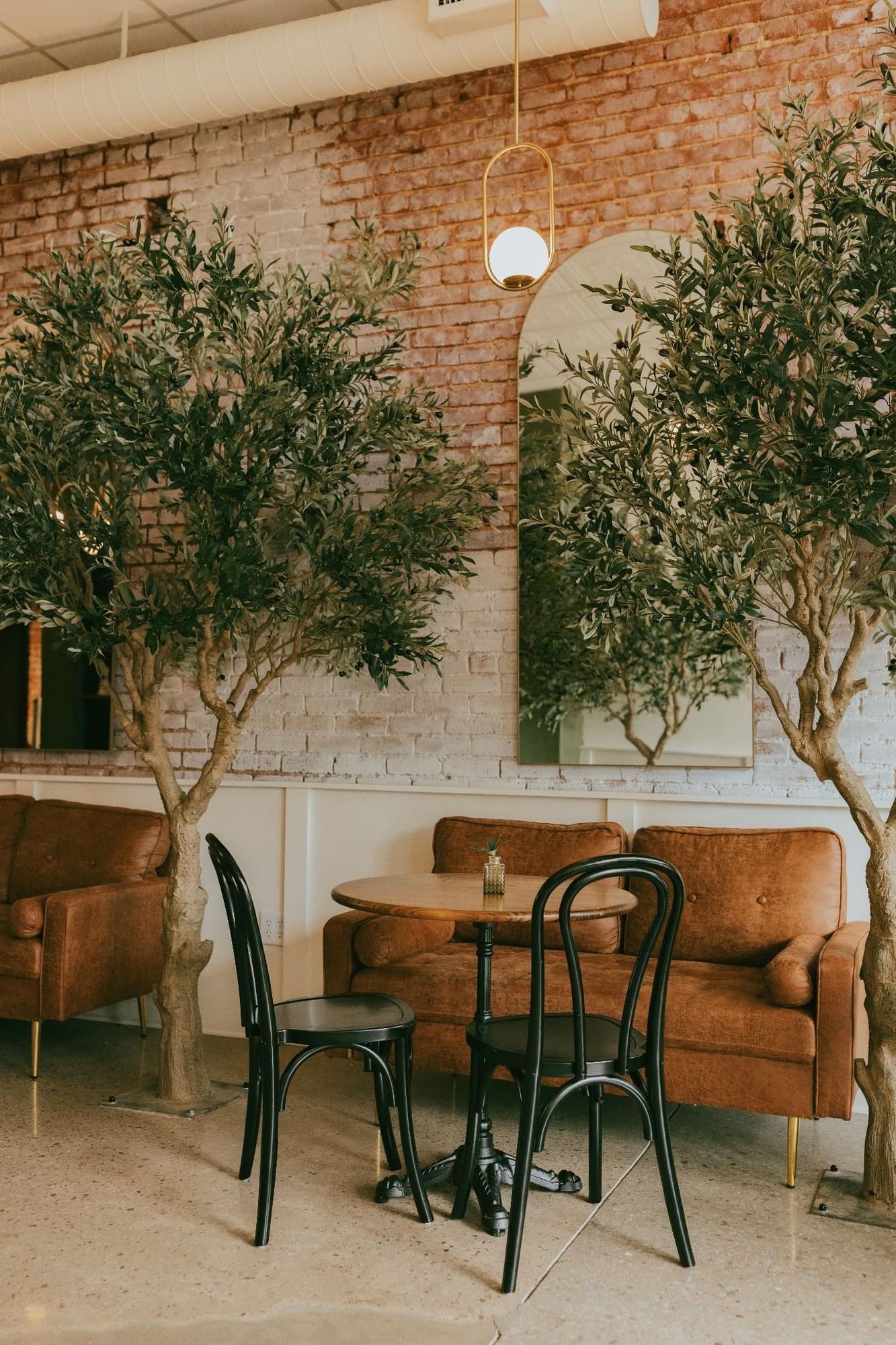 A cozy lobby area with a brown couch, small table, and black chairs.