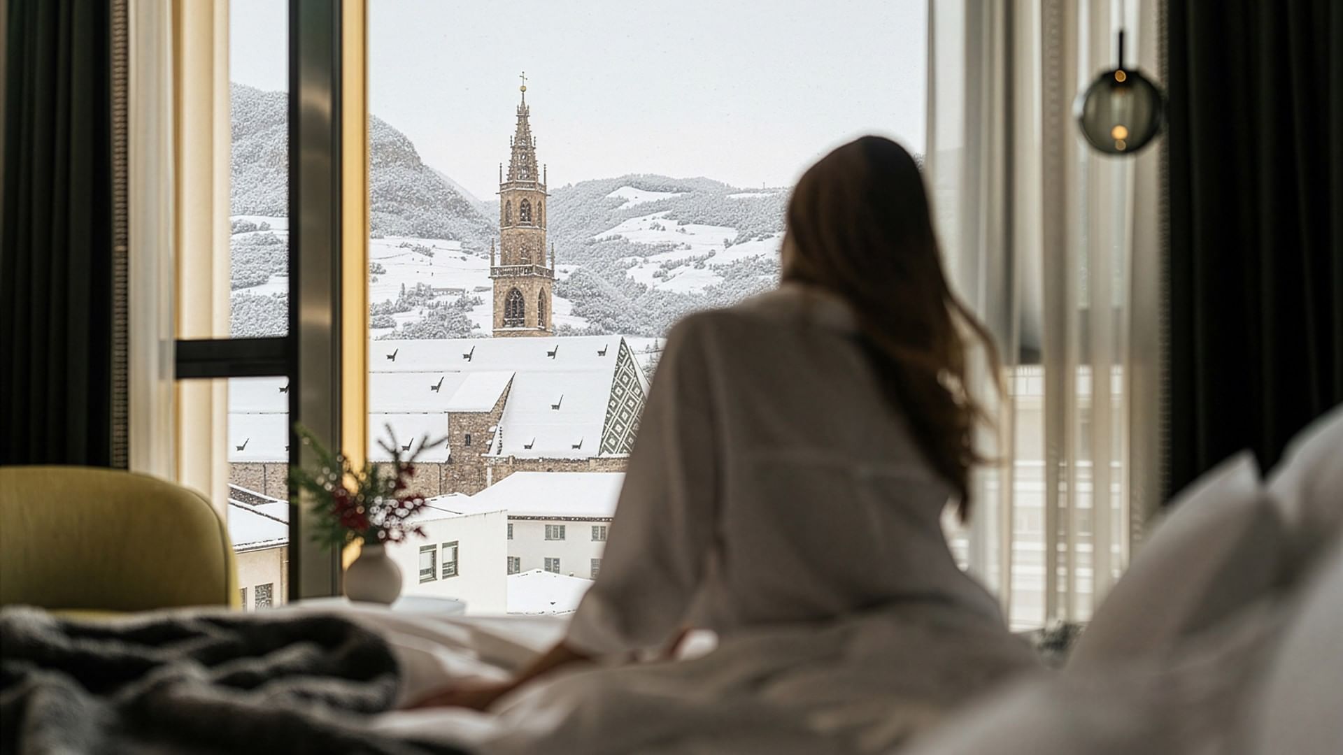 Frau im Hotelzimmer mit Blick auf eine verschneite Stadt und eine Kirche.