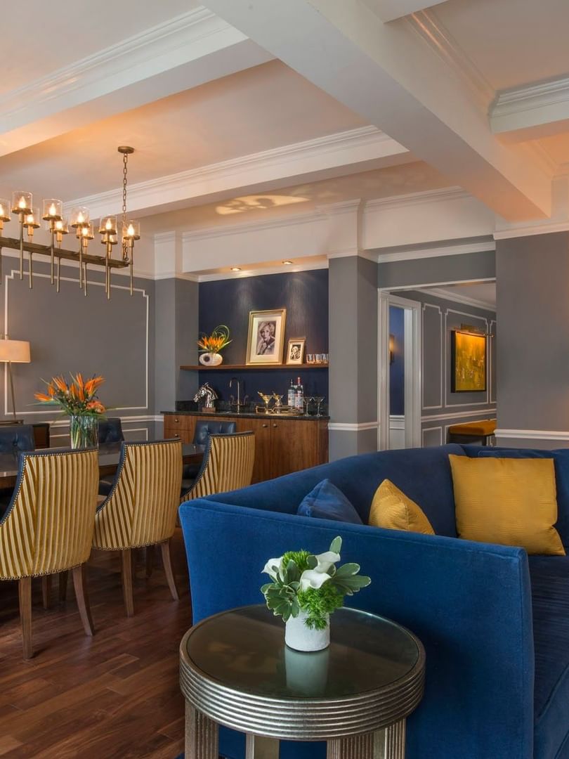 Sophisticated dining area featuring a long wooden table and a luxurious blue sofa set in Randolph Suite at Warwick New York