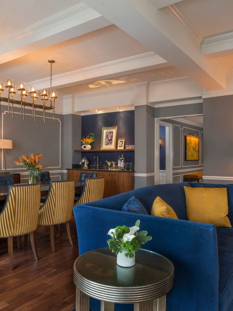 Sophisticated dining area featuring a long wooden table and a luxurious blue sofa set in Randolph Suite at Warwick New York