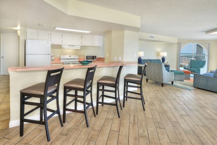 A wide view of a suite with a kitchenette, living area, and balcony
