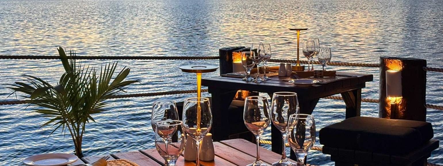 Tables with woven placemats and wine glasses by a railing in Wicked Walu at Warwick Fiji Resort and Spa