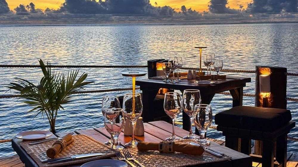Tables with woven placemats and wine glasses by a railing in Wicked Walu at Warwick Fiji Resort and Spa