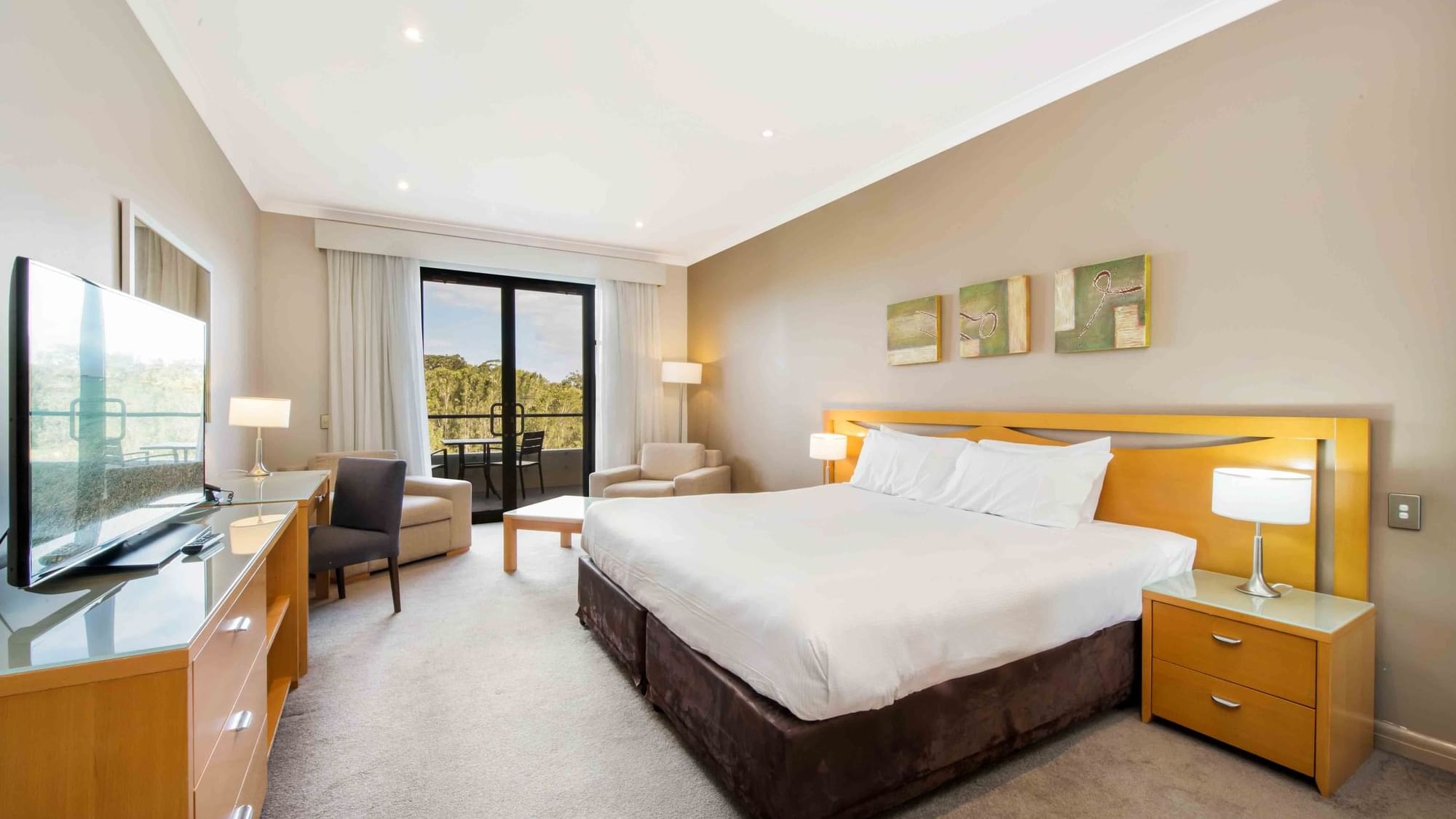 Deluxe Golf View Room with a large bed, seating area, and a balcony overlooking nature at Mercure Kooindah Waters