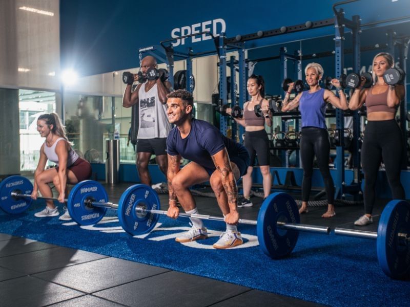 Guests lifting barbells and dumbbells during a group strength workout in the fitness center at Hotel X Toronto