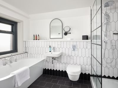 Contemporary Family Room bathroom at The Met Hotel Leeds, England, with a modern tub, glass shower, and geometric tiles