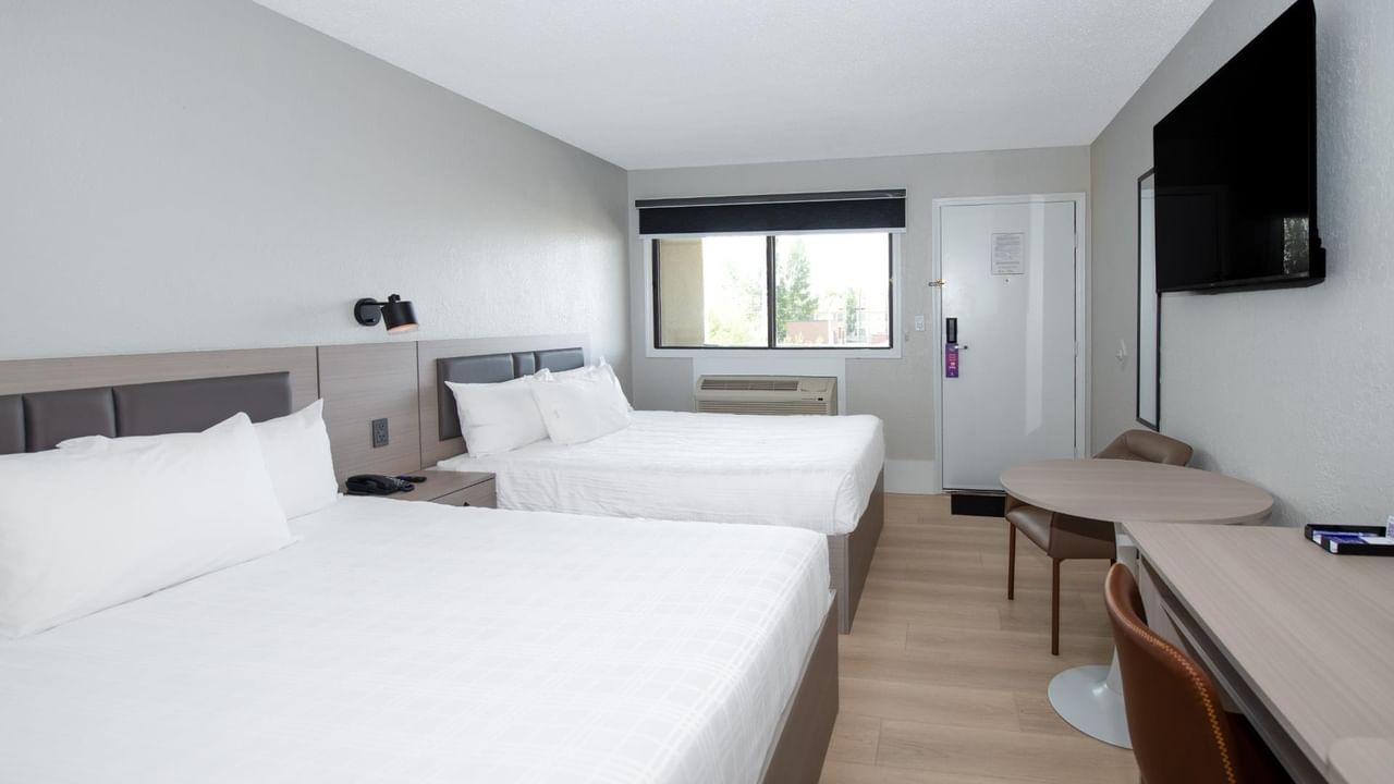 Guest room at Coast Red Deer Hotel with two queen beds, desk, TV and window