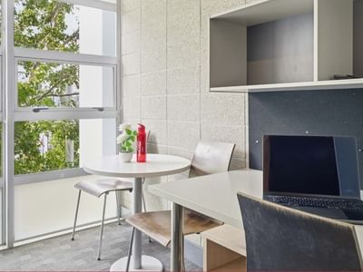 Laptop on desk and round table with chairs in Student Living Auckland - Beach.