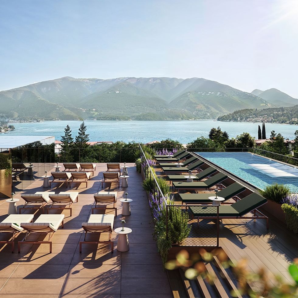 Terrasse mit Loungemöbeln, Pool und Blick auf den See und die Berge in der Ferne.