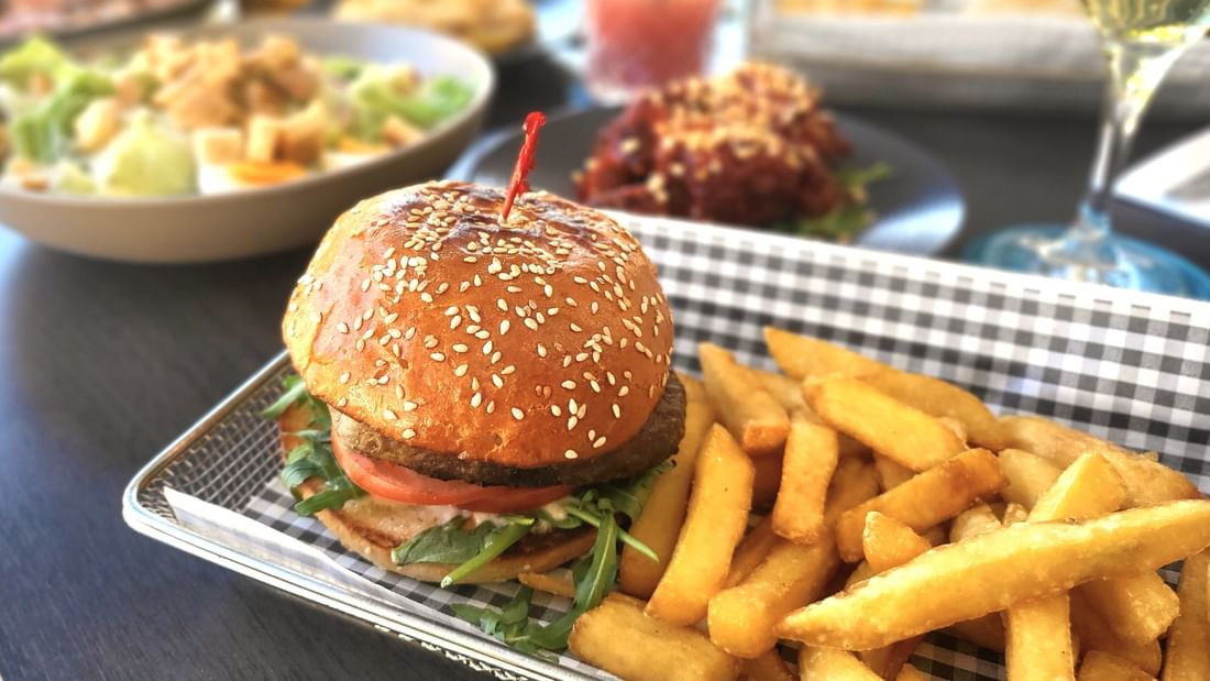 A sesame seed burger with lettuce, tomato, and sauce, served in Celsius Restaurant & Bar at Mercure Hotel Townsville