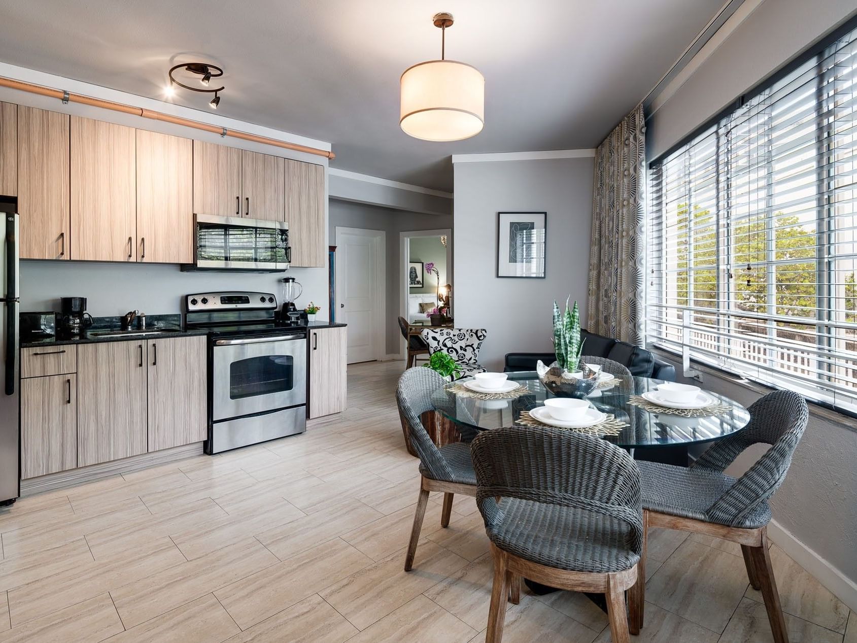 Two Bedroom Queen Suite kitchen with wood-look cabinetry and a dining table with woven chairs at Tradewinds Apartment Hotel