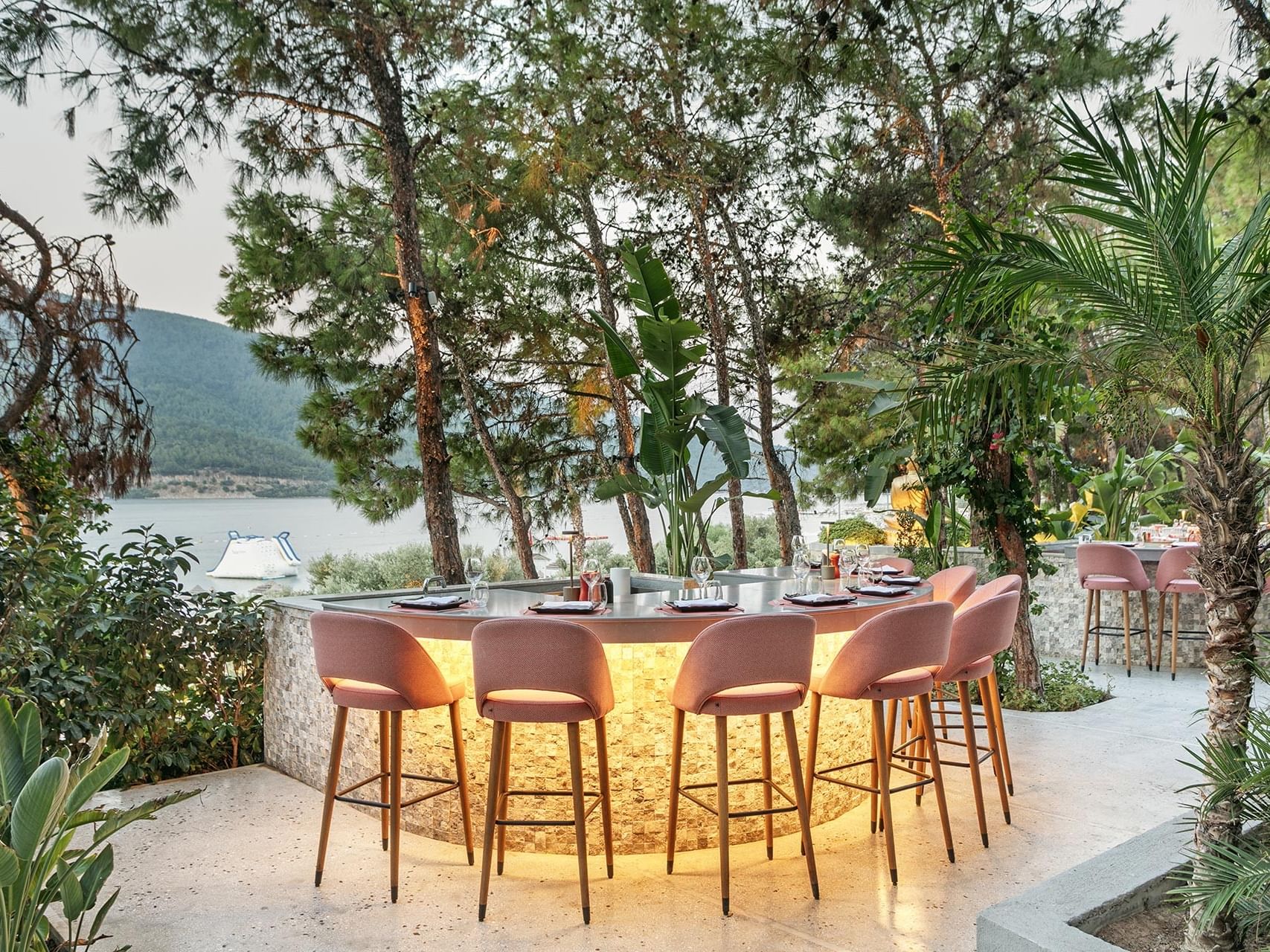 An outdoor restaurant at Titanic Luxury Collection Bodrum, surrounded by greenery and sea views.