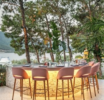 Titanic Luxury Collection Bodrum’daki Nori Restaurant’ta, yeşillikler içinde deniz manzaralı açık hava bar alanı.