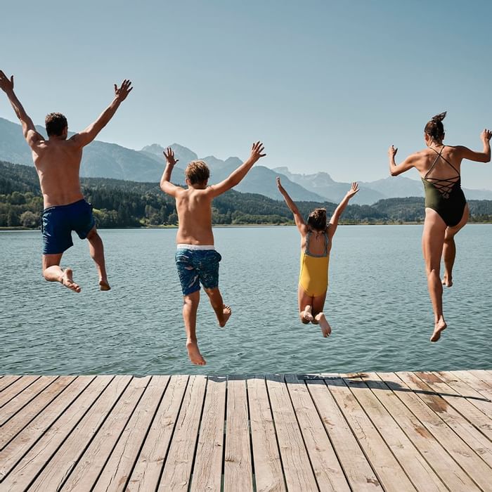 Family jumping off a dock into the lake near Falkensteiner Hotel Sonnenalpe