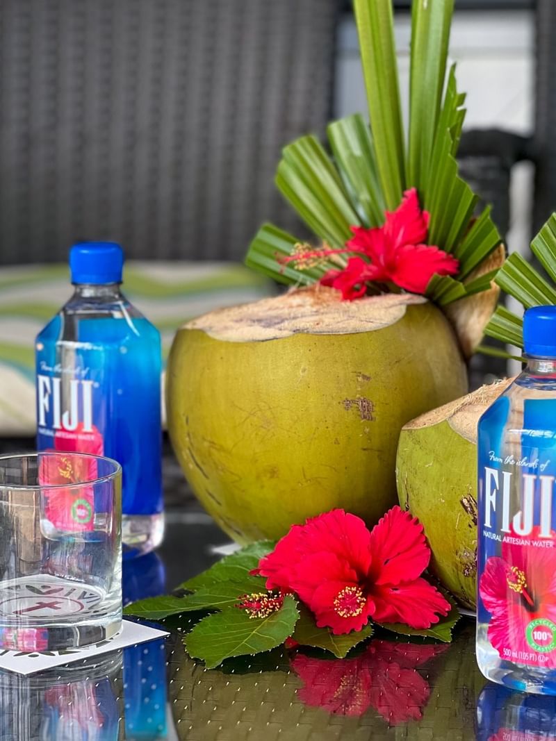 Coconuts, flowers, and Fiji water bottles on a table at Tokatoka Resort - Fiji International Airport in Nadi.