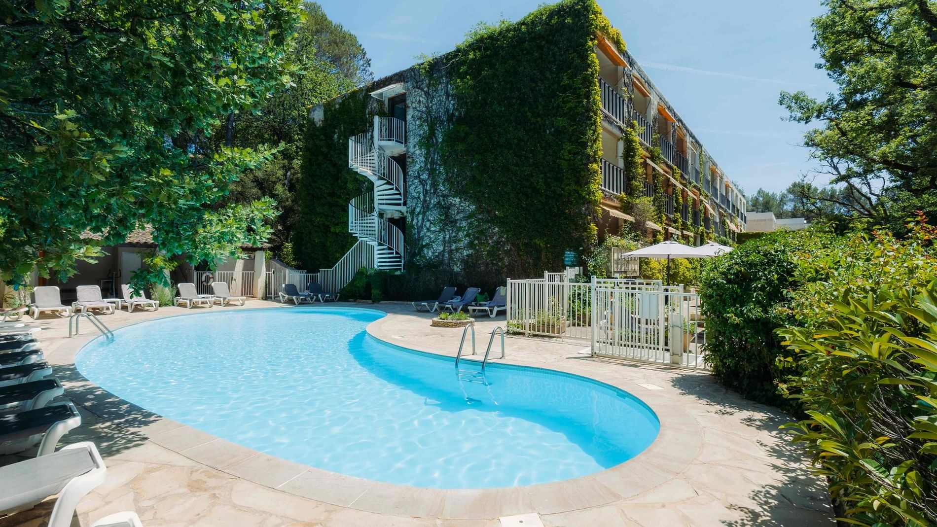 Curved outdoor swimming pool with lounge chairs beside an ivy-covered hotel exterior building at Villa Borghese